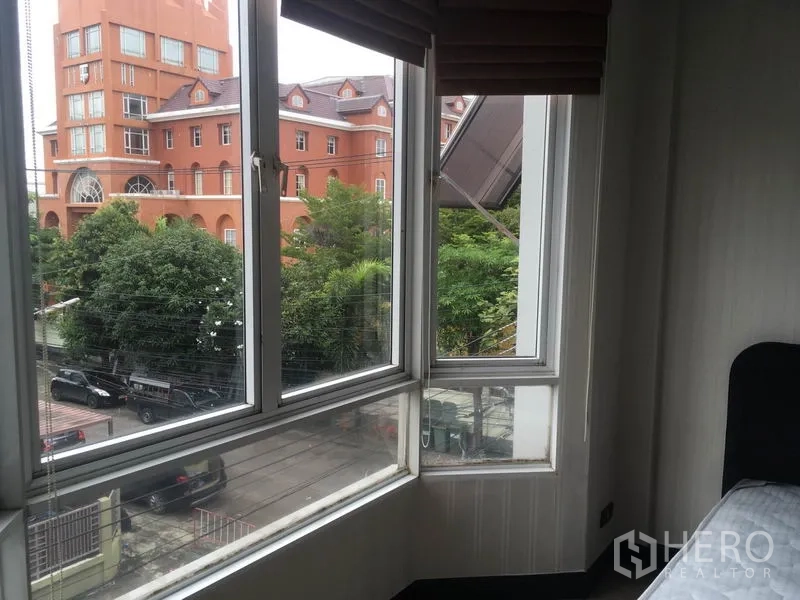 Townhouse for rent in Din Daeng, Bangkok - Corner window view over a quiet street and nearby orange building in Din Daeng.