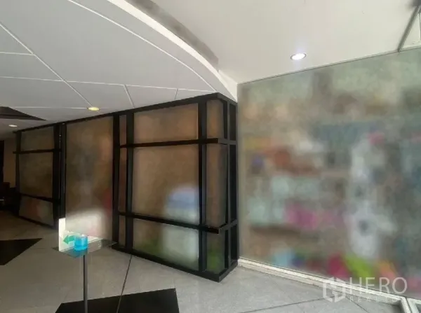 零售空间 出租在Watthana, Bangkok - 室内走廊视角，黑色框架玻璃隔断与弧形白色天花。