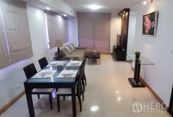 Condominium for rent in Watthana, Bangkok - Open-plan living and dining room with glass-top table, sofa, and neutral blinds.