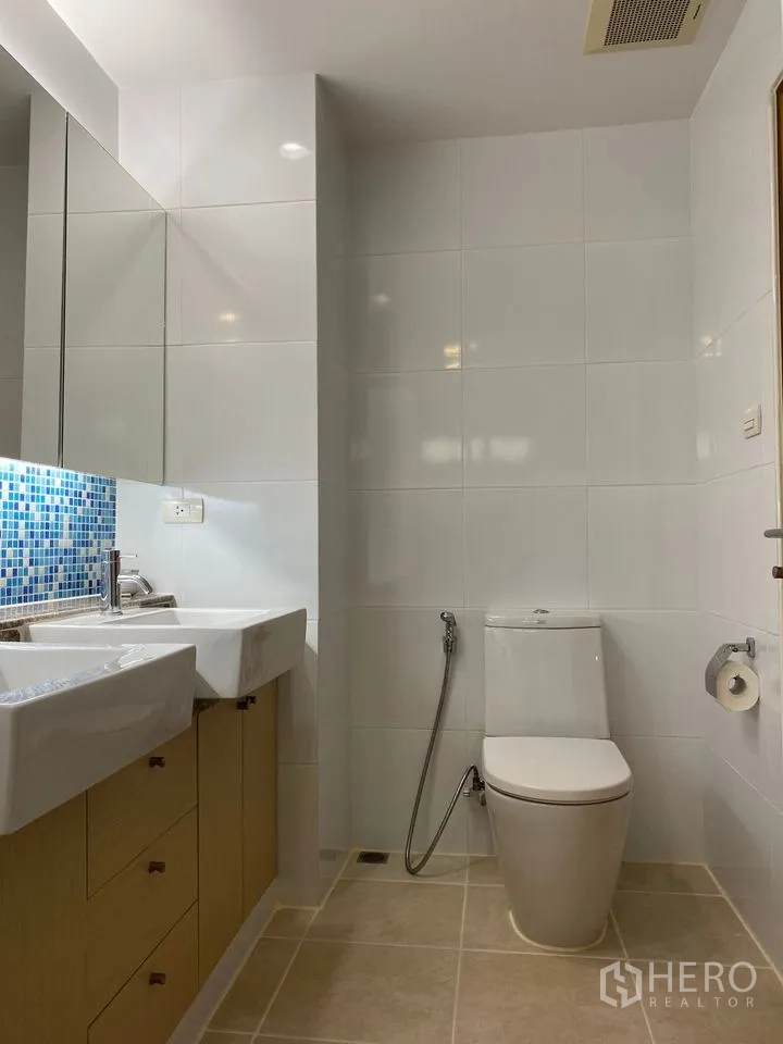 Condominium for rent or sale in Phra Khanong, Bangkok - Modern bathroom with twin basins, toilet and mosaic-tile backsplash.