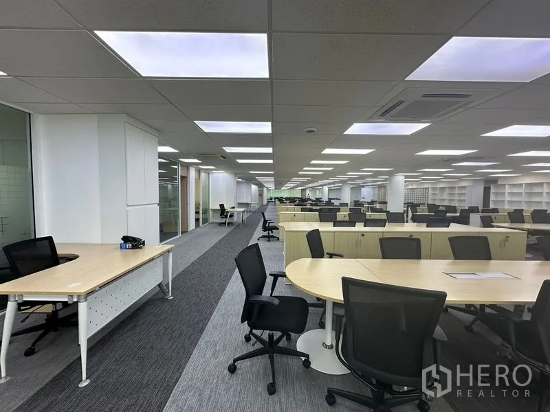 Office Space for rent - Panoramic view down open office with desks, glass meeting rooms and shelving.