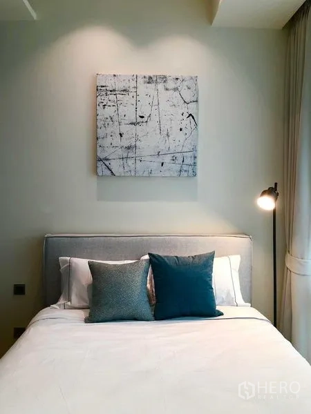 Condominium for rent - Bedroom with artwork above the bed, teal accent pillows and a floor lamp.