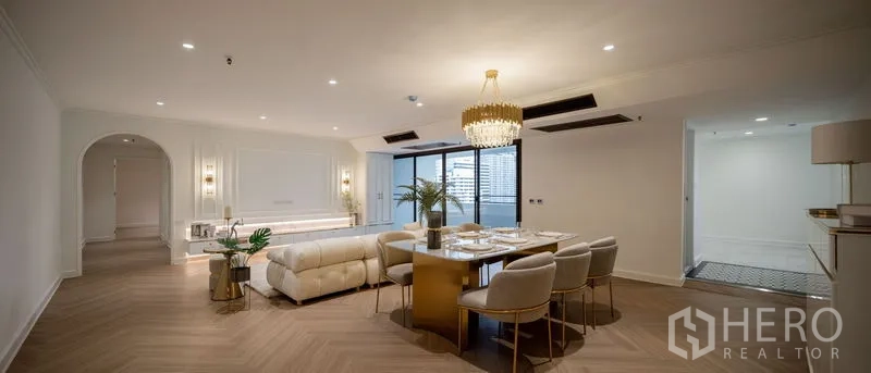 Condominium for sale in Watthana, Bangkok - Open-plan living and dining room with a chandelier and sliding doors to the balcony.