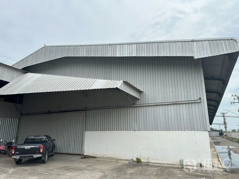 Factory for rent in Pathum Thani - Metal-clad warehouse exterior with covered loading bay and parking area.