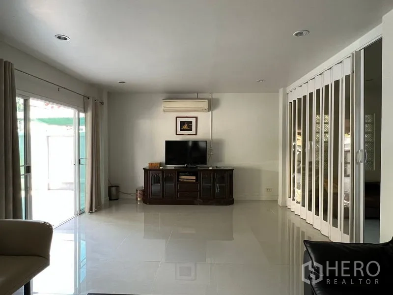 独立式住宅 出租在Bang Kapi, Bangkok - 客厅配电视柜，推拉落地门通向露台，并设折叠隔断。