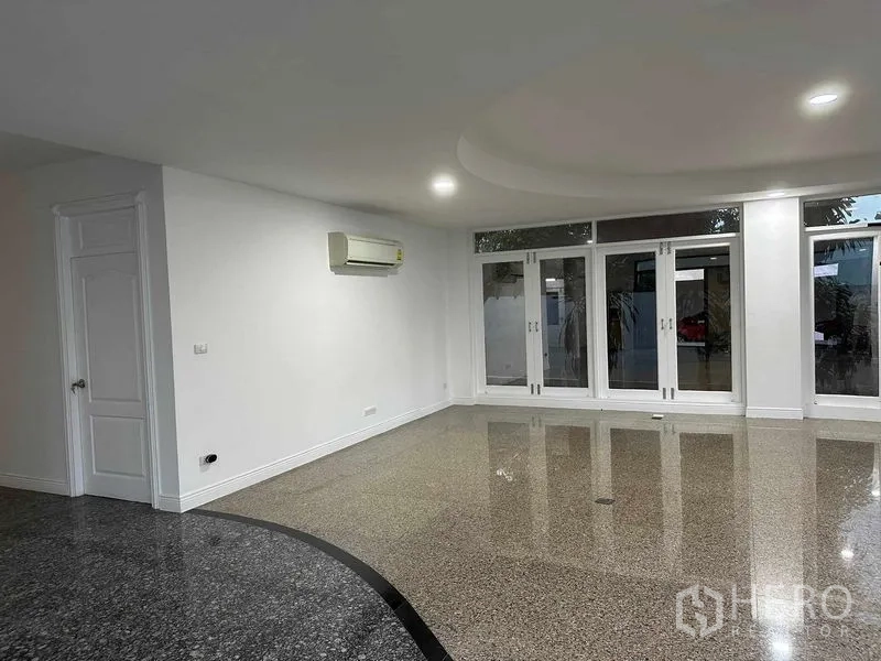 Home Office for sale - Living area with glossy terrazzo floor, recessed ceiling and multiple glass doors to the patio.