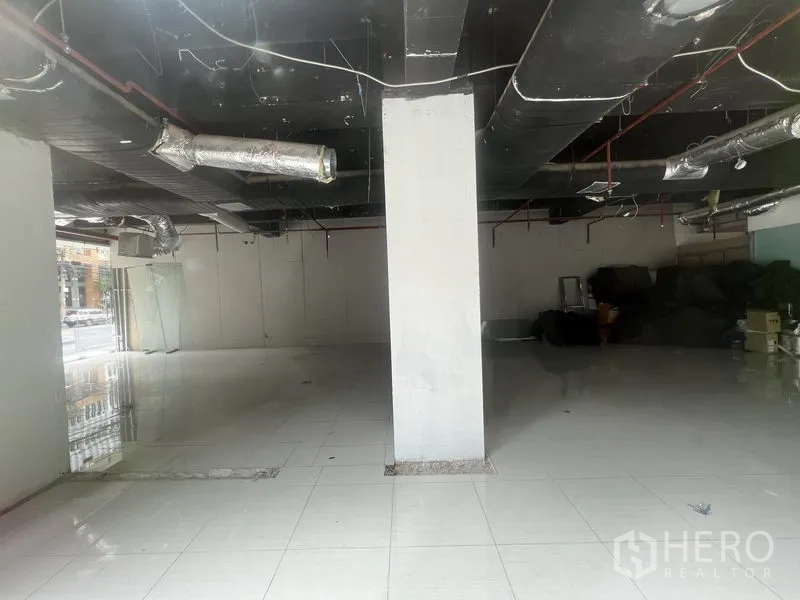 零售空间 出租在Watthana, Bangkok - 大开间零售楼层，设中央柱、瓷砖地面与黑色外露设备。