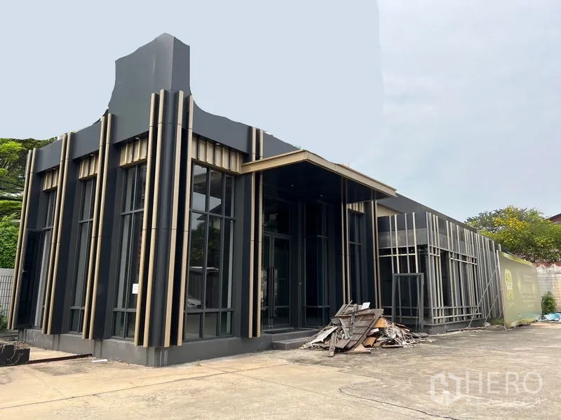 零售空间 出租在Chatuchak, Bangkok - 建筑侧视图与入口，玻璃门面宽阔，前场可供顾客停车。