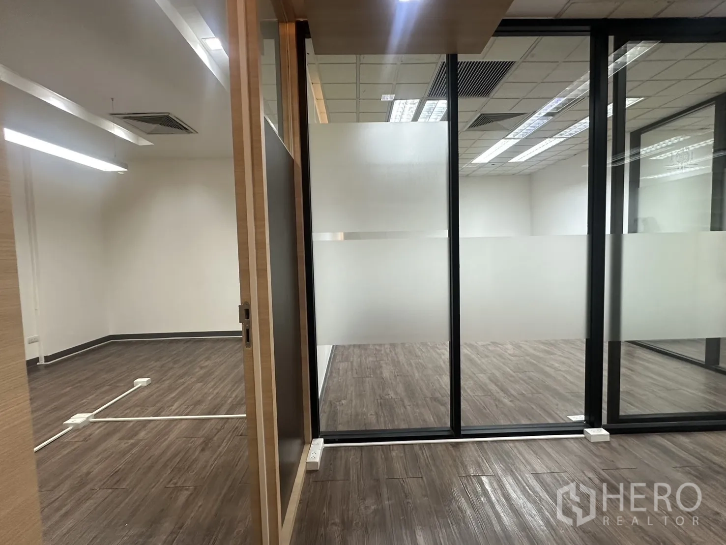 ออฟฟิศ for rent in Pathum Wan, Bangkok - ประตูบานเลื่อนเชื่อมสู่ห้องทำงานกั้นด้วยผนังกระจกฝ้าและพื้นโทนไม้เข้ม