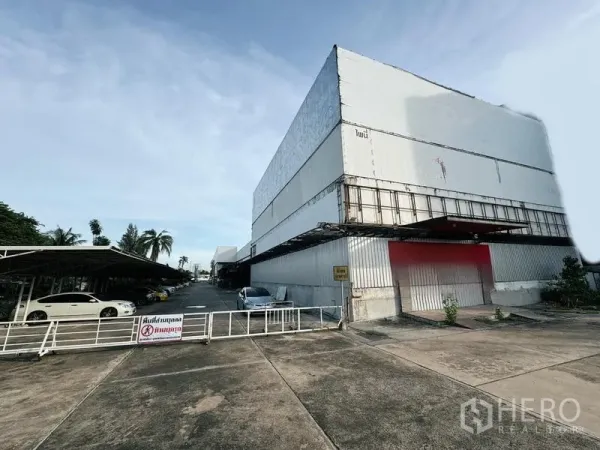 展厅 出租在Min Buri, Bangkok - 民武里带围栏的工业展示厅外观，金属板建筑与宽阔车道。