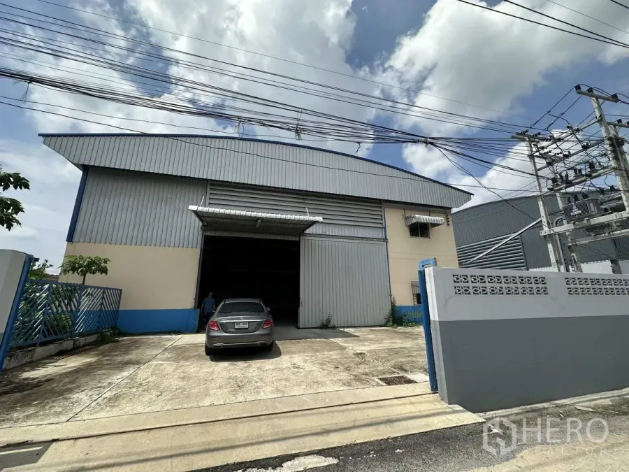 Factory for rent in Pathum Thani - Gated factory exterior with wide sliding door and concrete driveway in Lat Lum Kaeo, Pathum Thani.