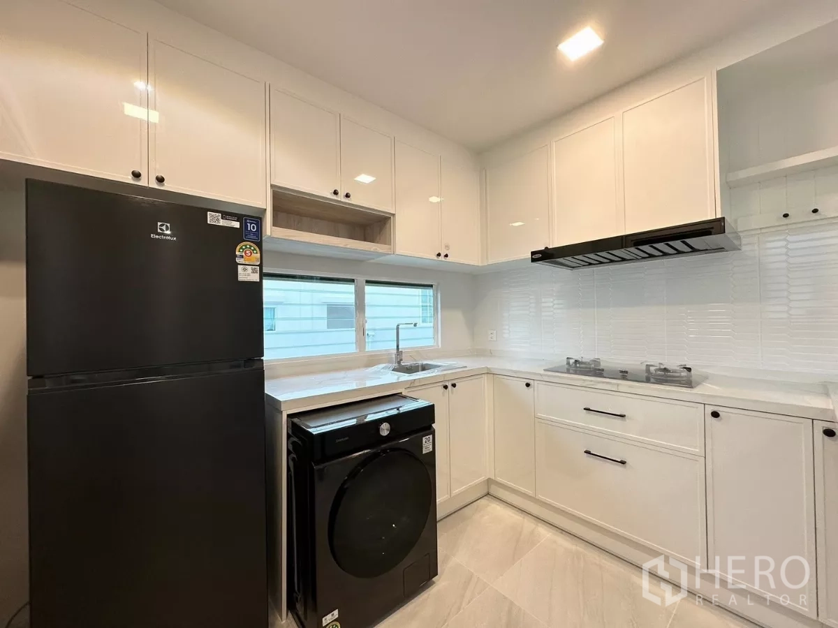 独立式住宅 出租在Bang Phli, Samut Prakan - 白色整体厨房，配燃气灶、油烟机与吧台式传菜窗。