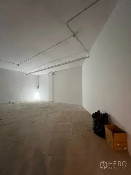 พื้นที่ขายปลีก ให้เช่า - มุมห้องโชว์ผนังขาวเรียบ เดินท่อบนเพดาน และพื้นยกระดับ