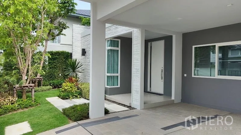 บ้าน ให้เช่าในPrawet, Bangkok - ชานทางเข้าพร้อมที่จอดรถในร่ม ประตูบ้านสีขาวใหญ่ และสวนแต่งเรียบร้อย