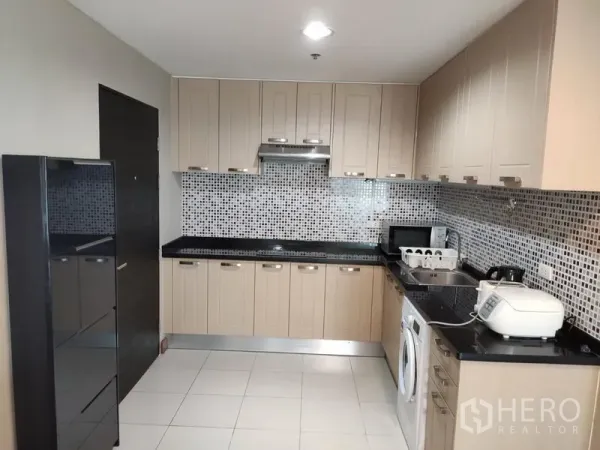 Condominium for rent in Huai Khwang, Bangkok - Spacious modern kitchen with ample cabinetry, hob and hood, tile floors and appliances.