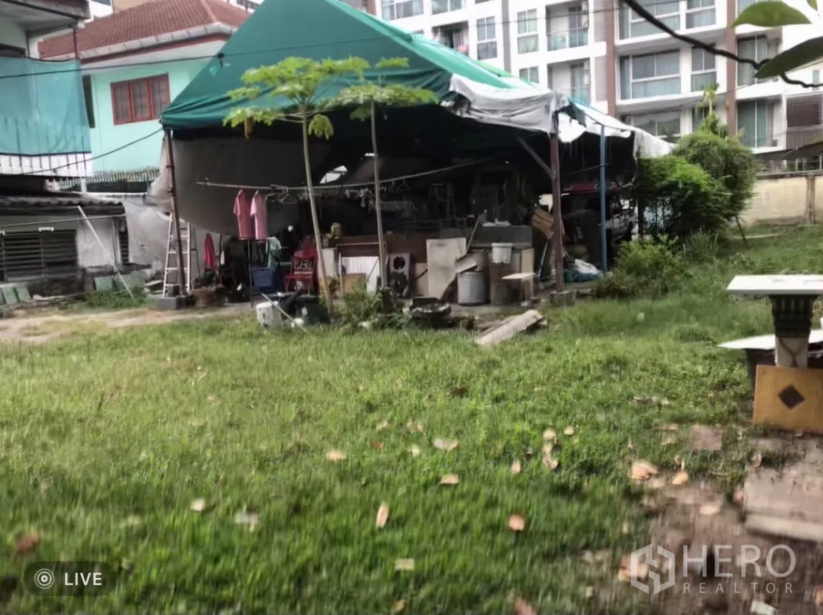 ที่ดิน ขายในPhra Khanong, Bangkok - ลานหญ้าโล่งภายในแปลงพร้อมเต็นท์ชั่วคราว มีอาคารพักอาศัยสูงปานกลางด้านหลัง.