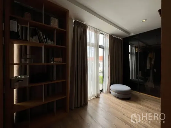 联排别墅 出租在Saphan Sung, Bangkok - 舒适的书房或更衣区，落地窗帘、内置书架与圆形脚凳。