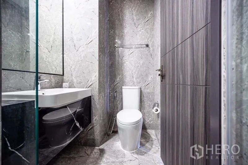 Condominium for rent in Watthana, Bangkok - Contemporary bathroom with gray marble tiles, toilet and vanity sink.