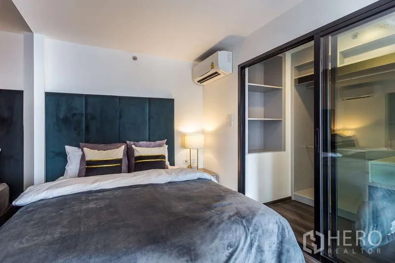 Condominium for rent or sale - Bedroom view showing bedside lamp and glass door to the closet.