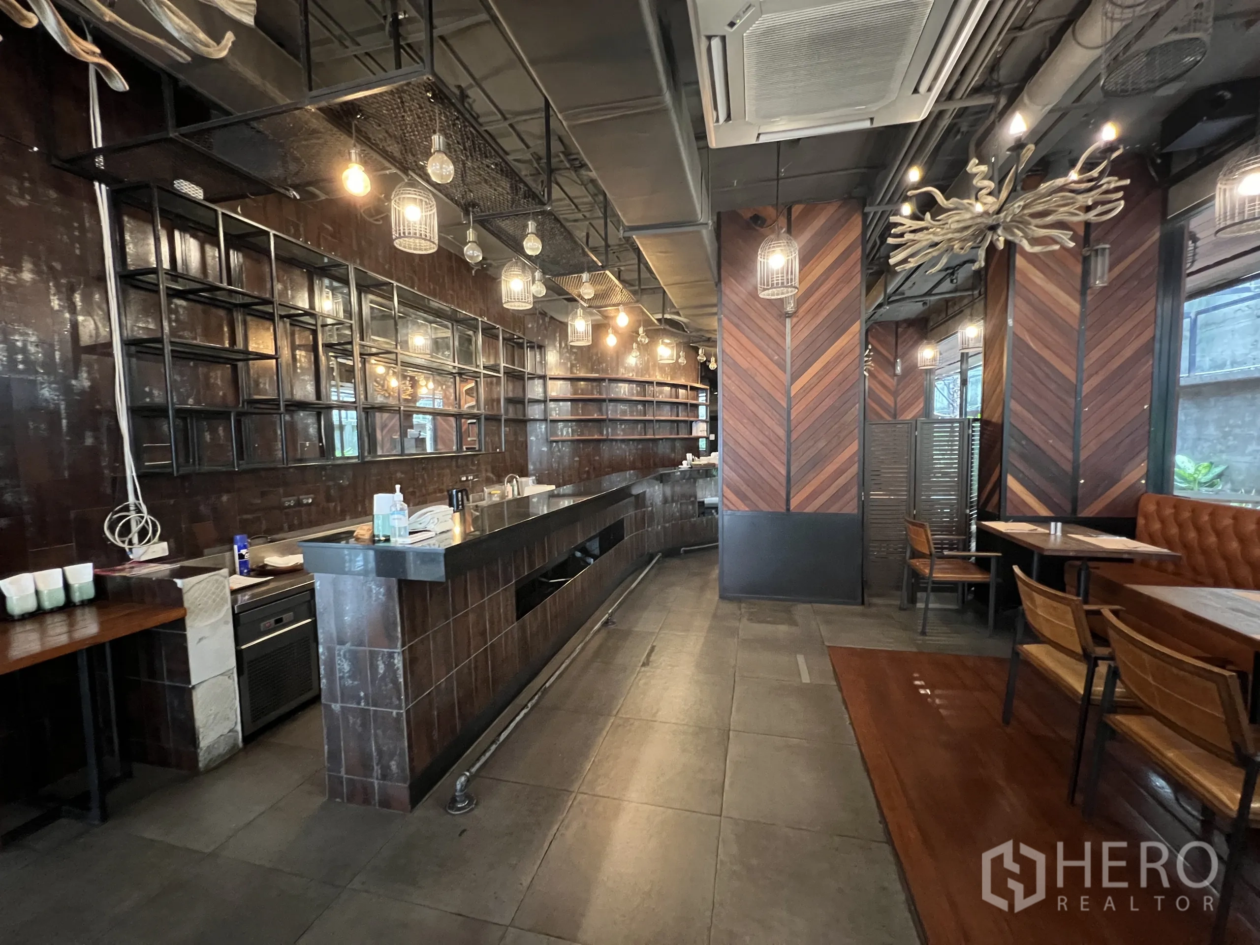 พื้นที่ขายปลีก ให้เช่าในWatthana, Bangkok - เคาน์เตอร์บาร์ยาว ชั้นวางเปิด เพดานสไตล์อินดัสเทรียล โคมไฟกรง และเบาะนั่งบูธ