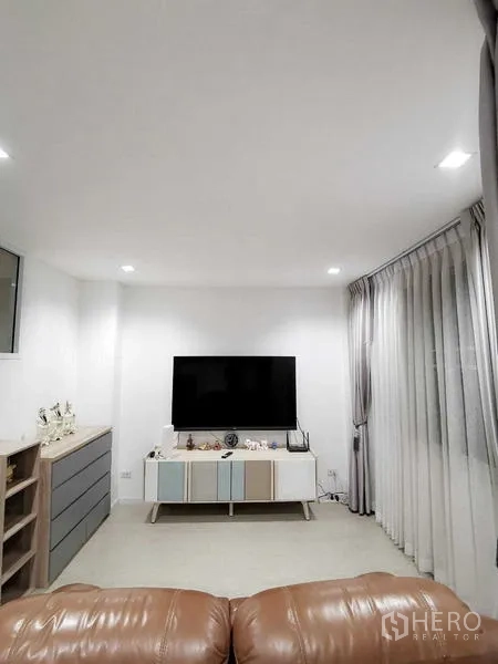 Home Office for rent or sale - TV room with leather recliner, media console and sheer curtains.