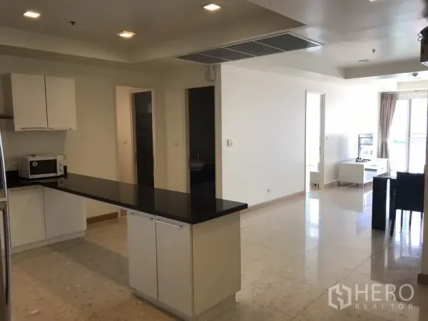 Condominium for rent in Khlong Toei, Bangkok - Spacious open kitchen with long black countertop island facing the living area.