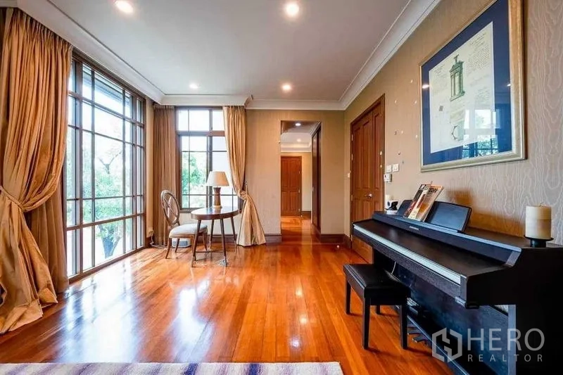 Detached House for sale - Sitting area with upright piano, small round table and floor-to-ceiling windows.