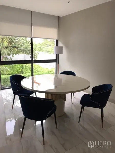 บ้าน ให้เช่าในWatthana, Bangkok - มุมทานอาหารสว่าง โต๊ะกลมสีขาว เก้าอี้สีน้ำเงินสี่ตัว ข้างหน้าต่างบานใหญ่พร้อมมู่ลี่ และพื้นหินอ่อน