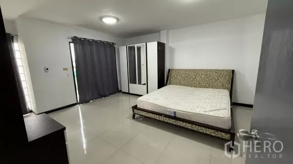 带办公室的家 出租在Bang Na, Bangkok - 大卧室，花纹靠背床、衣柜，推拉门连接阳台与遮光窗帘。