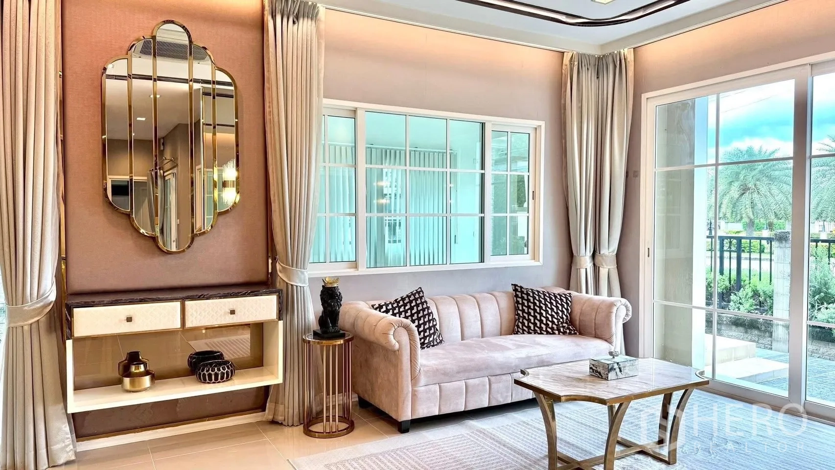 Detached House for rent or sale in Bueng Kum, Bangkok - Bright living room with blush sofa, gold mirror, long curtains and sliding doors opening to the garden.