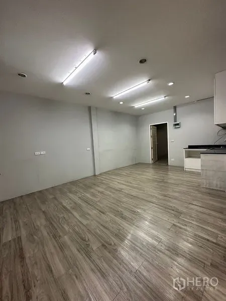 พื้นที่ขายปลีก ให้เช่าในKhlong Toei, Bangkok - พื้นที่เปิดโล่ง ผนังสีเทา พื้นลายไม้ ไฟเพดาน และประตูสู่พื้นที่บริการ