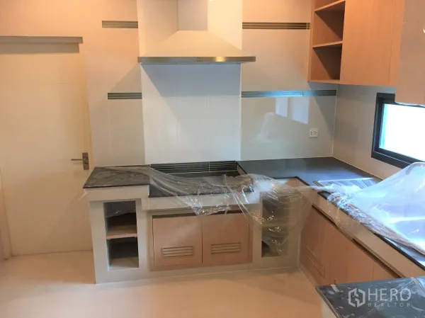 Detached House for rent or sale in Bang Kapi, Bangkok - Fitted kitchen with range hood, stone countertops and light wood cabinetry.
