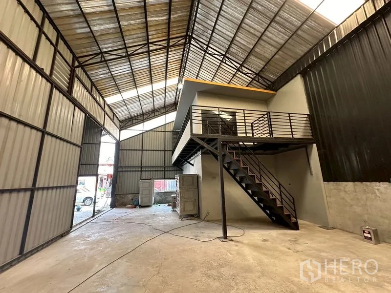 Warehouse for rent in Lat Phrao, Bangkok - Ground‑level view of the warehouse interior with mezzanine office and staircase.