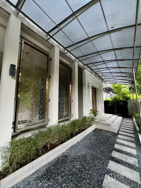Detached House for rent or sale in Prawet, Bangkok - Covered side walkway with patterned metal window screens and a neat planter bed.