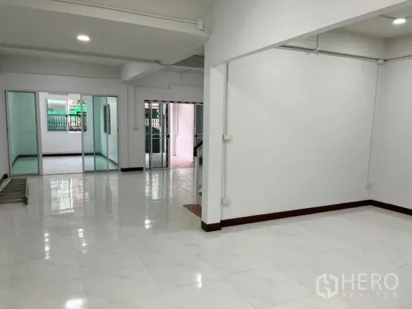 联排别墅 出租在Din Daeng, Bangkok - 明亮的开放式客厅，光滑瓷砖地面，带推拉玻璃门分隔空间。