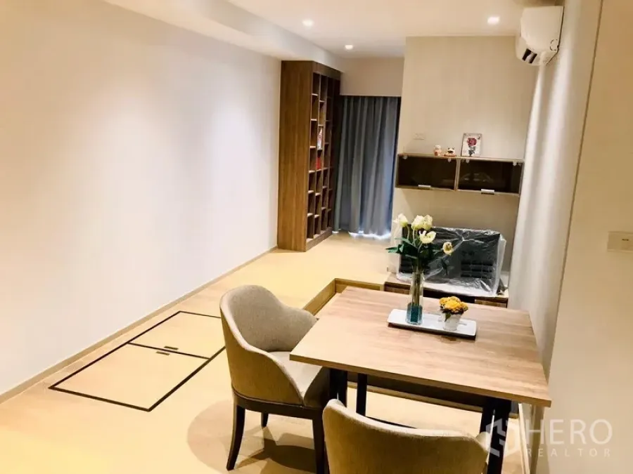 Condominium for rent or sale in Watthana, Bangkok - Minimalist dining nook beside a raised tatami-style living platform with wood shelving and soft recessed lighting.