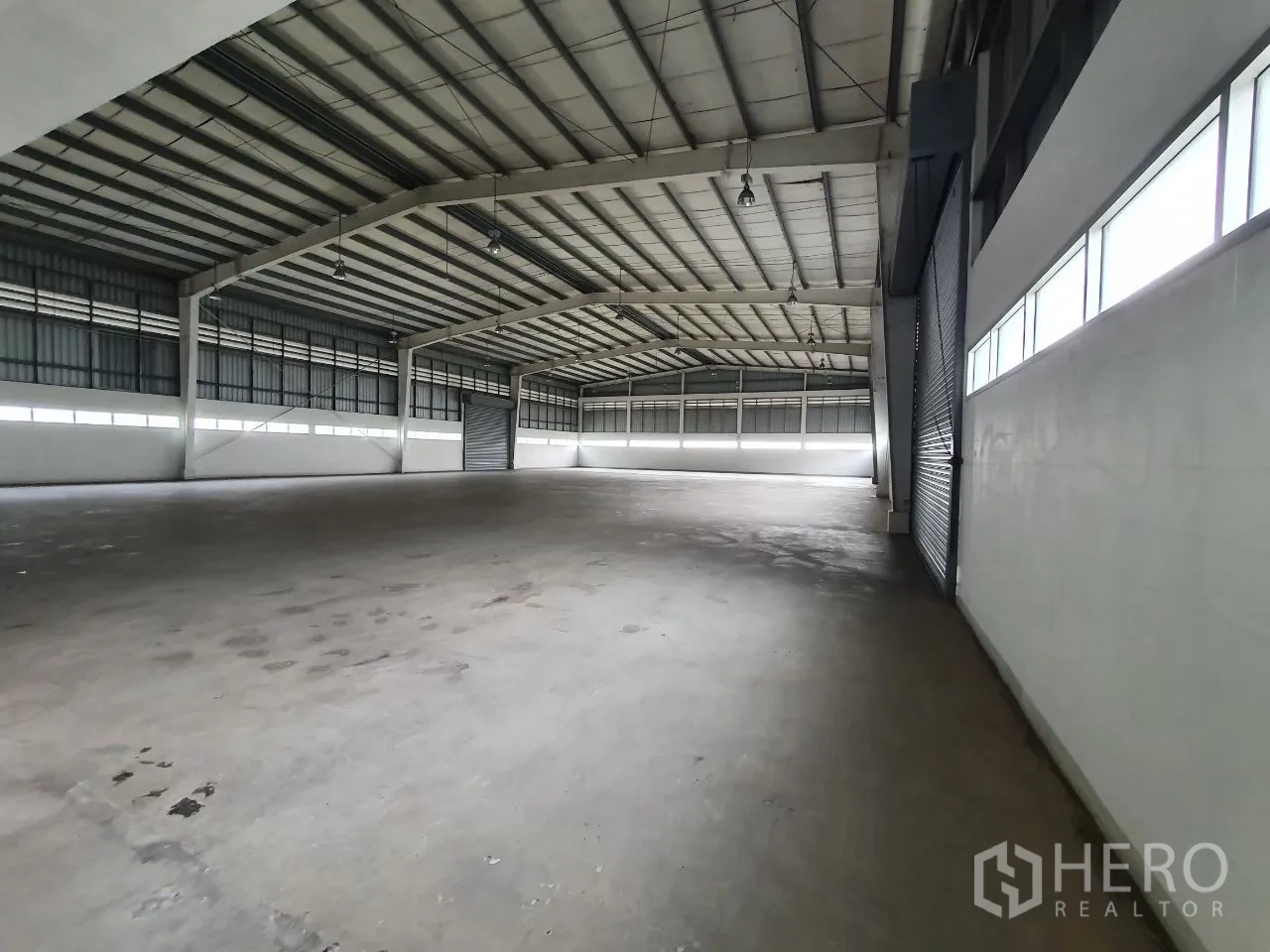 Factory for rent in Bang Pa-in, Phra Nakhon Si Ayutthaya - Spacious high-ceiling warehouse interior with concrete floor and windows.