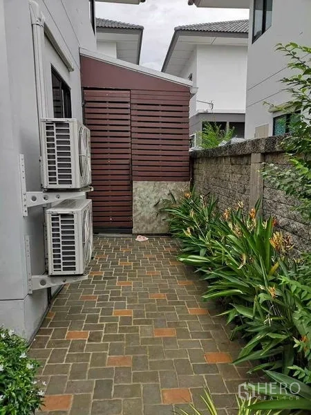 Detached House for sale in Bang Phli, Samut Prakan - Brick side walkway with exterior AC compressor units, plants and a privacy wall