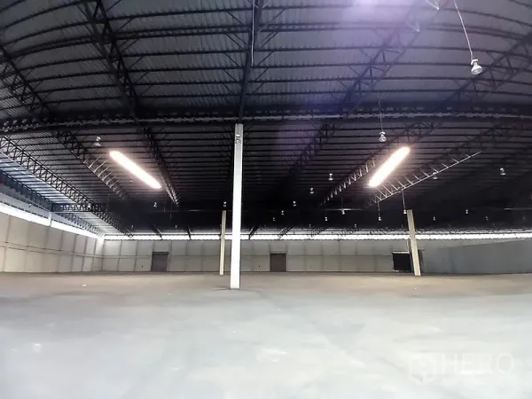 Warehouse for rent in Bang Pakong, Chachoengsao - Open warehouse bay with steel truss roof, bright strip lights and multiple loading doors.