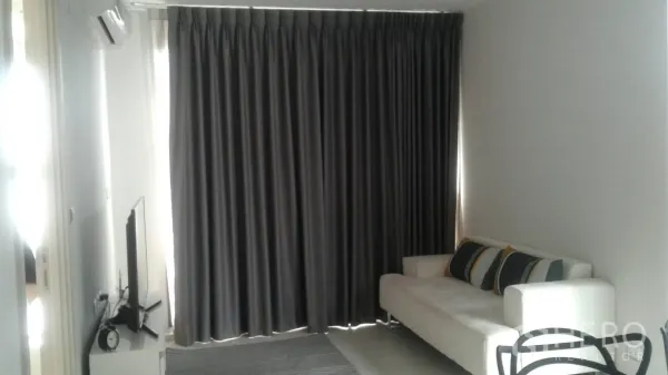 公寓 出租在Khlong Toei, Bangkok - 明亮客厅，白色沙发、电视柜，整面遮光窗帘。