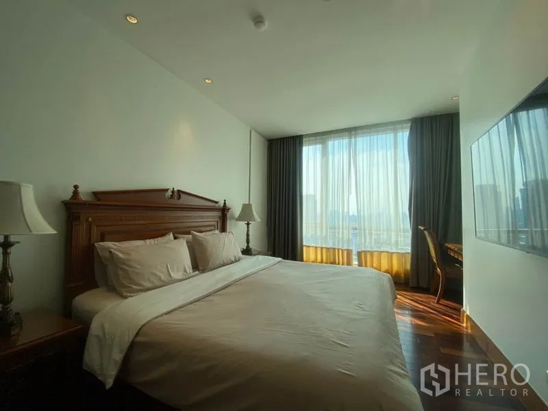 公寓 出租在Sathon, Bangkok - 主卧配特大床、床头灯、超大窗户及书桌，可赏城市景观。