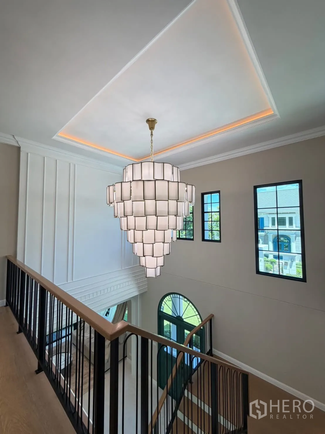 Detached House for rent in Saphan Sung, Bangkok - Upper landing with statement chandelier, black railings, and arched window.