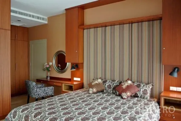 คอนโด ให้เช่าในWatthana, Bangkok - ห้องนอนหลัก ผ้าปูและหมอนลาย ตู้เสื้อผ้าบิลท์อิน โต๊ะเครื่องแป้ง และผนังหัวเตียงลายริ้วโทนอุ่น