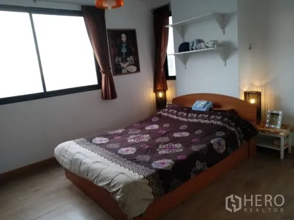 Condominium for rent in Watthana, Bangkok - Corner bedroom with large windows, wooden bed and ambient lighting.