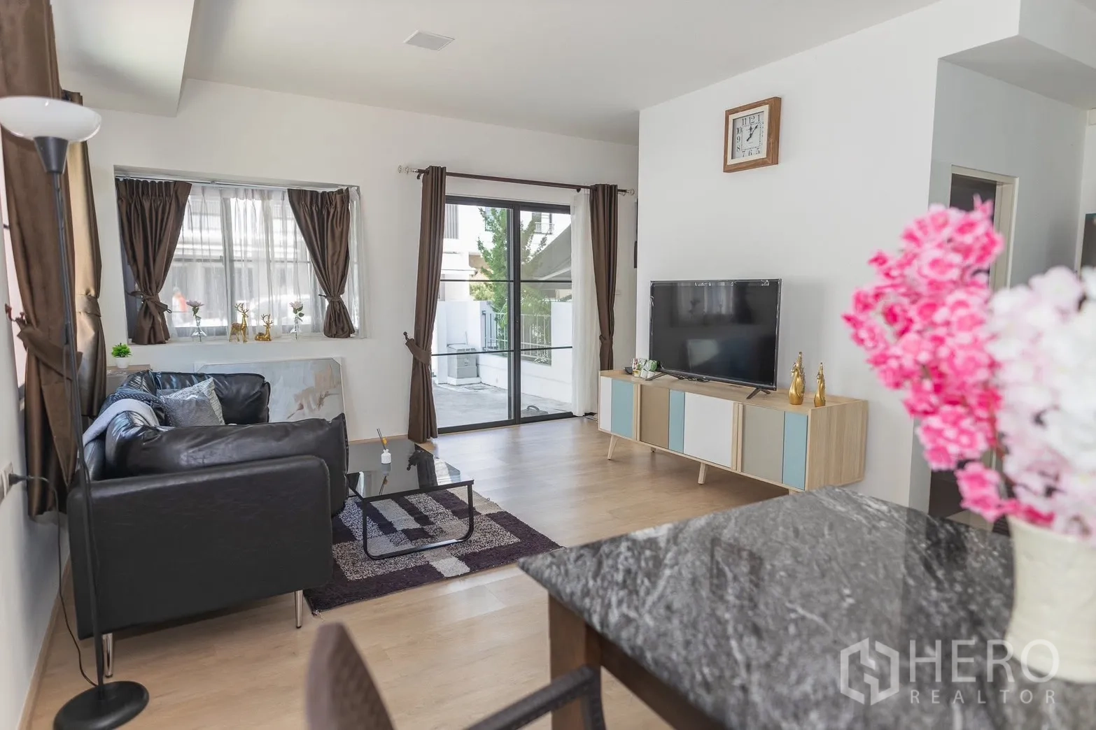 Townhouse for rent in Bang Phli, Samut Prakan - Living room with sofa, TV console, and sliding doors to the patio.