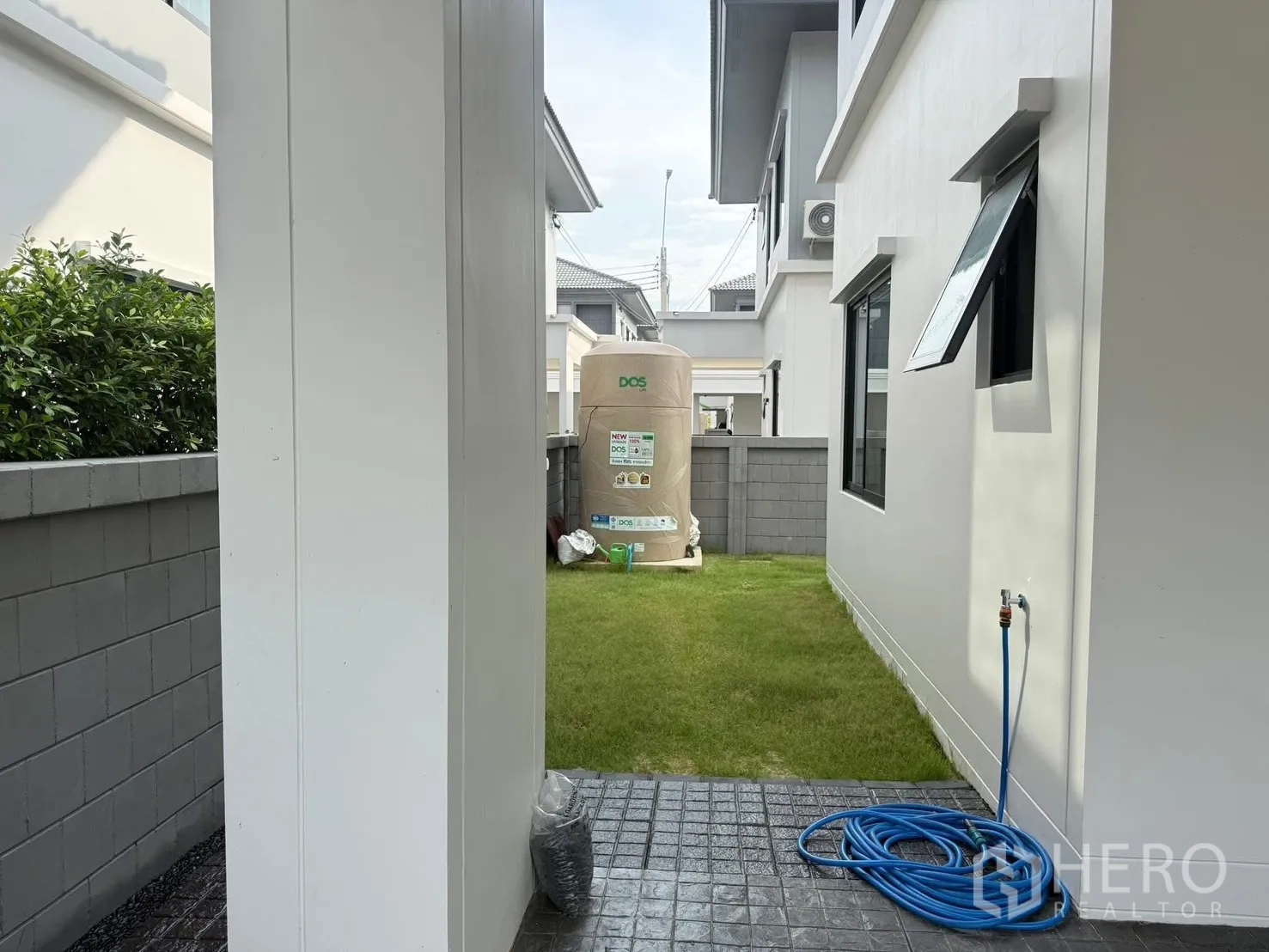 Detached House for rent in Bang Phli, Samut Prakan - Side yard with green lawn, water tank and outdoor tap next to the house.