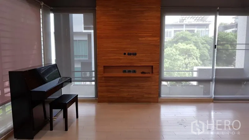 สำนักงานที่บ้าน ขายในWang Thonglang, Bangkok - ห้องนั่งเล่นสว่างผนังไม้พร้อมหน้าต่างบานใหญ่และเปียโน