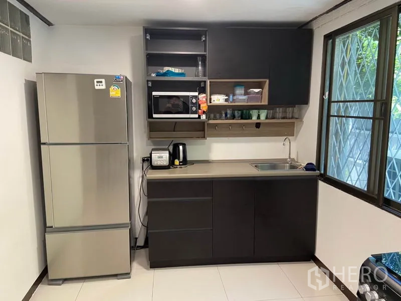 ทาวน์เฮาส์ ให้เช่าในKhlong Toei, Bangkok - ครัวบิวท์อินโทนเข้ม มีตู้เย็นสแตนเลส ไมโครเวฟ อ่างล้างจาน และหน้าต่างเหล็กดัด