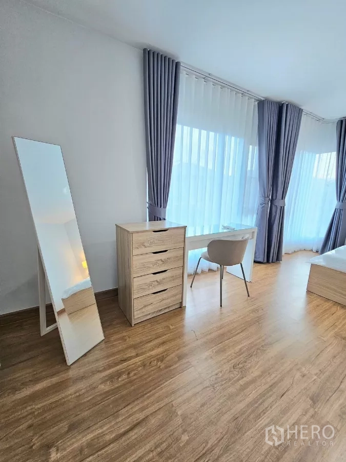 Detached House for rent in Bang Phli, Samut Prakan - Bedroom corner with drawer chest, standing mirror and desk beside panoramic windows.