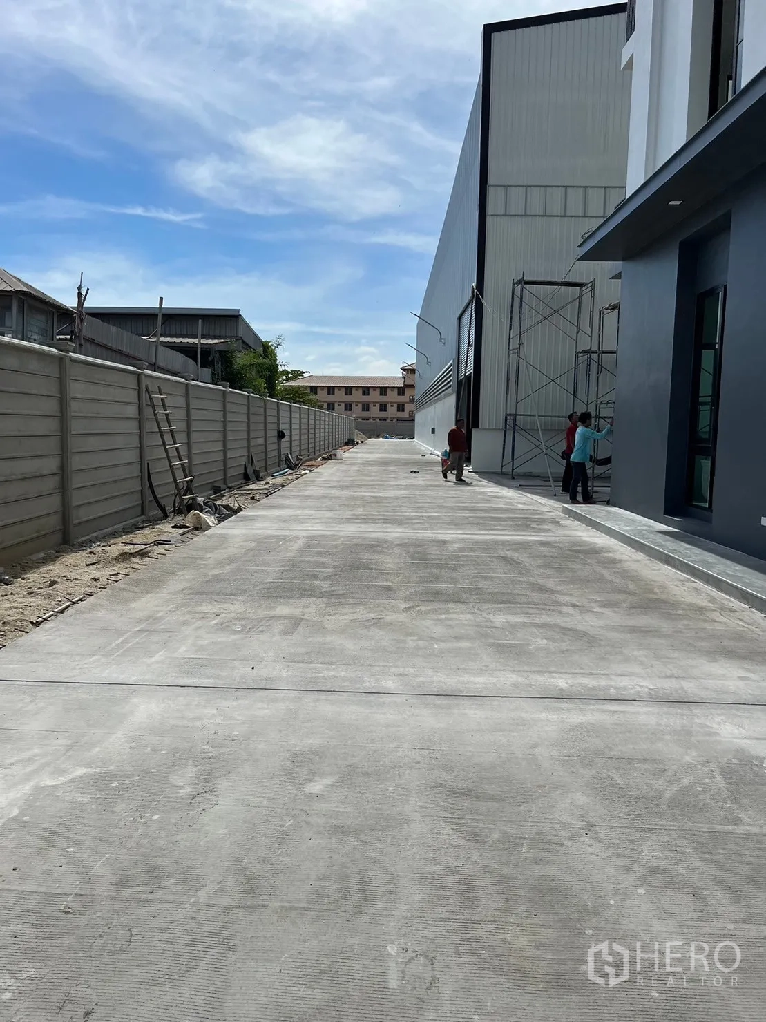 货栈 出租在Bang Sao Thong, Samut Prakan - 仓库与办公楼旁的长混凝土车道与围墙。